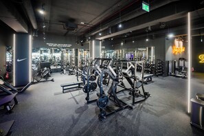 Un gimnasio con equipo de ejercicio variado, un espejo grande y mensajes motivacionales en la pared.