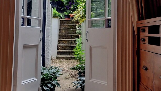 A wooden staircase leading to a garden with potted plants and hanging flowers. - Annette's Place, Greenwich (London) - Garden Apartment (close to the O2 Arena) (London)