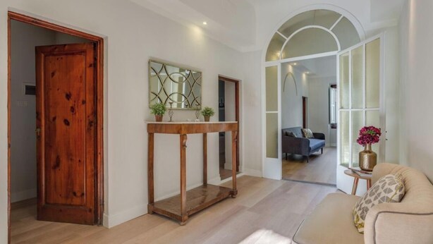A spacious living area with a wooden door, a console table with plants, and a sofa with a vase of flowers. - Stunning Holiday Apartment in the Heart of Florence (Firenze)
