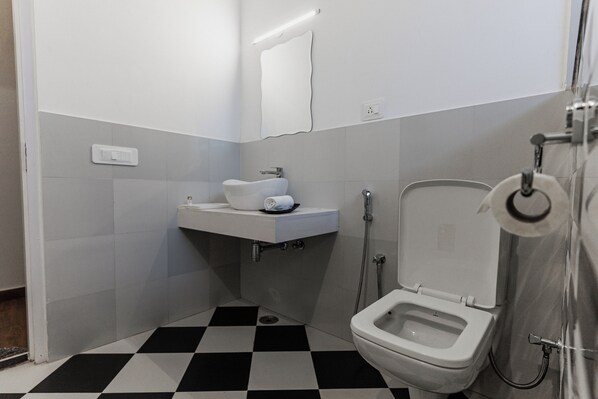 A bathroom with a white sink, a toilet, and a shower.