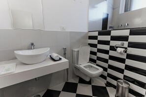 A bathroom with a white sink, a toilet, and a black and white checkered floor.