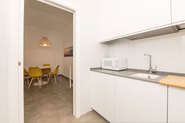 A modern kitchen with white cabinets, a grey countertop, a microwave, and a sink. - Urban Palace in Sanlucar de Barrameda (Sanlucar de Barrameda)