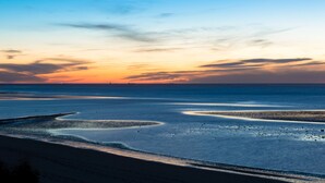 Una playa con una luna creciente y una puesta de sol.