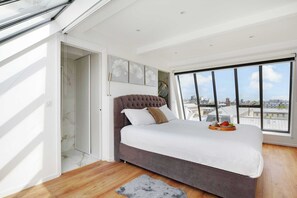A modern bedroom with a large bed, a city view through floor-to-ceiling windows, and a skylight. - Résidence Paris Rochechouart (Paris)