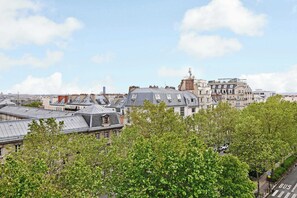 A cityscape with historic buildings, a clear sky, and a bus stop. - Résidence Paris Rochechouart (Paris)