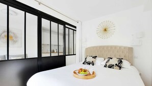 A modern bedroom with a large bed, a breakfast tray, and a decorative wall piece. - Résidence Paris Rochechouart (Paris)