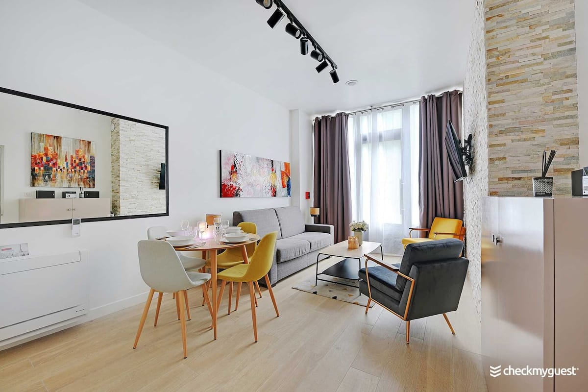 Un salon moderne avec un coin repas, comprenant un canapé, des fauteuils, une table basse et des œuvres d’art accrochées aux murs.