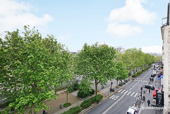 A street view with trees lining the road, a bus lane, and a hotel sign. - Résidence Paris Rochechouart (Paris)