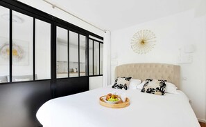 A modern bedroom with a large bed, a breakfast tray, and a decorative wall piece. - Résidence Paris Rochechouart (Paris)