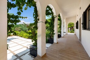 A covered corridor with arches, a tiled patio, and greenery. - 4147 Villa Daversa by Barbarhouse (Manduria)
