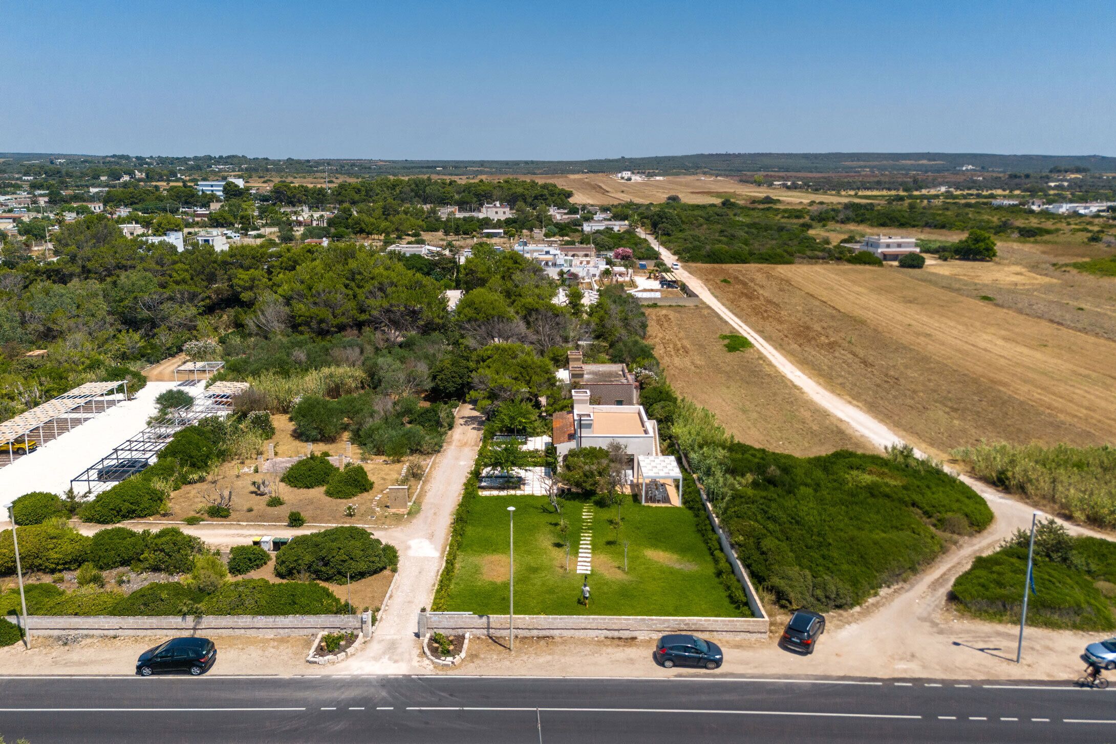 An aerial view of a residential area with houses, a road, and a green space.