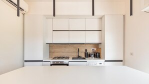 A modern kitchen with white cabinets, a wooden backsplash, a gas stove, a coffee maker, and a dishwasher. - 4147 Villa Daversa by Barbarhouse (Manduria)