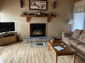 Cozy living room with a fireplace, flat-screen TV, and comfortable sofa.
