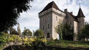 A historic stone building with a prominent tower and a bridge in the foreground. - Château-l'evêque en Périgord (Château-l'Évêque)