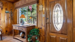 Interior de madeira com uma porta grande com design em vitral, uma escrivaninha com abajur e uma janela com a bandeira dos Estados Unidos.