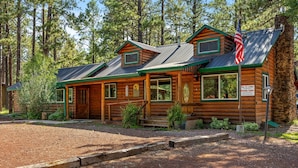 Uma cabana rústica de madeira com telhado de metal, uma bandeira e uma placa indicando que é uma cabana particular.