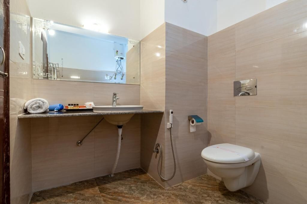 Un baño con lavamanos, espejo e inodoro.