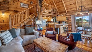 Un accogliente interno di una baita in legno, con una scala in legno, un'area pranzo e una cucina.