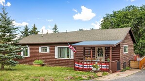 A log cabin with a porch, American flags, and a small garden. - Cottage Room on Main (Greer)