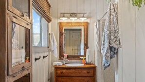 A bathroom with a wooden vanity, a large mirror, and a shower curtain. - Cottage Room on Main (Greer)