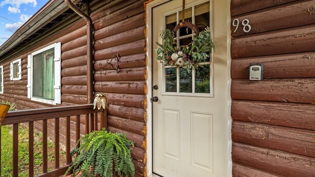 A wooden cabin with a white door, a number '98, and a wreath on the door. - Cottage Room on Main (Greer)