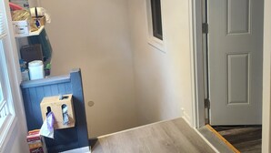 Ein Flur mit Holzboden, einer Tür mit Fenster und einem kleinen Fenster an der Wand.