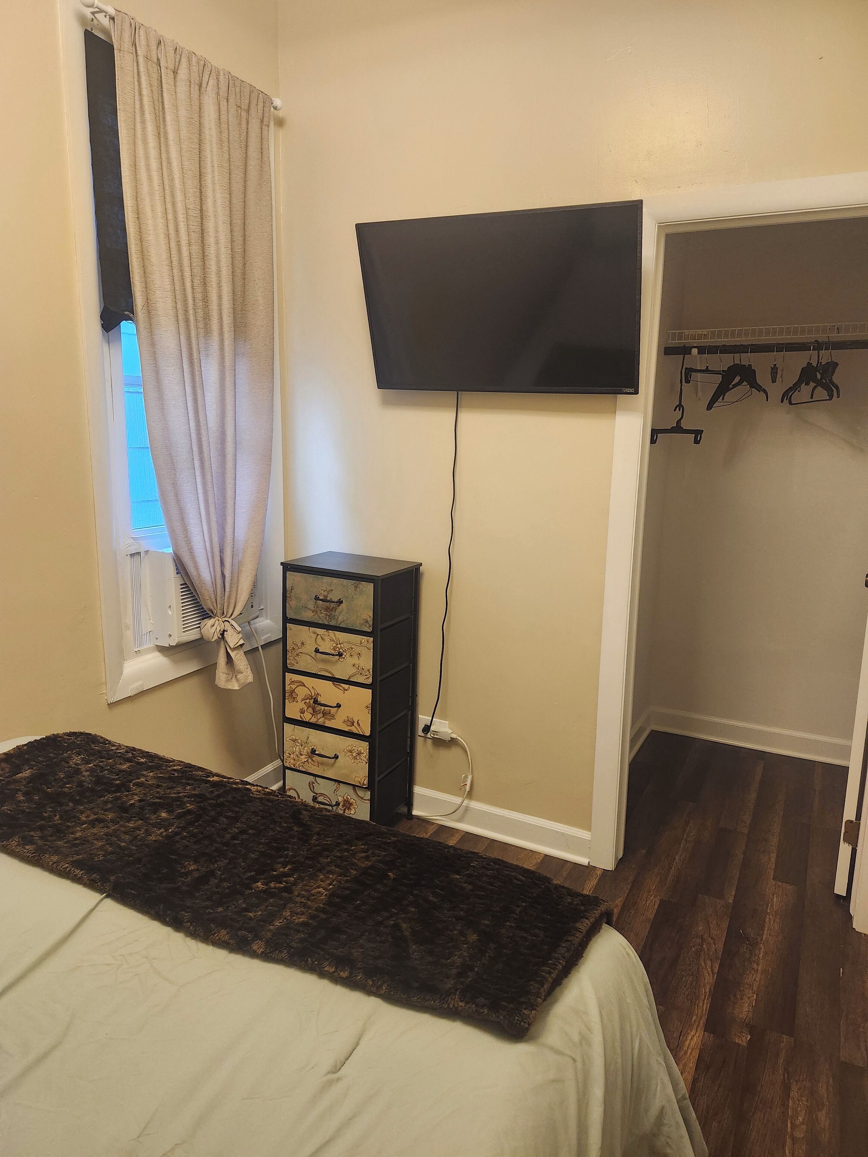 Quarto com cama, penteadeira, televisão e armário.