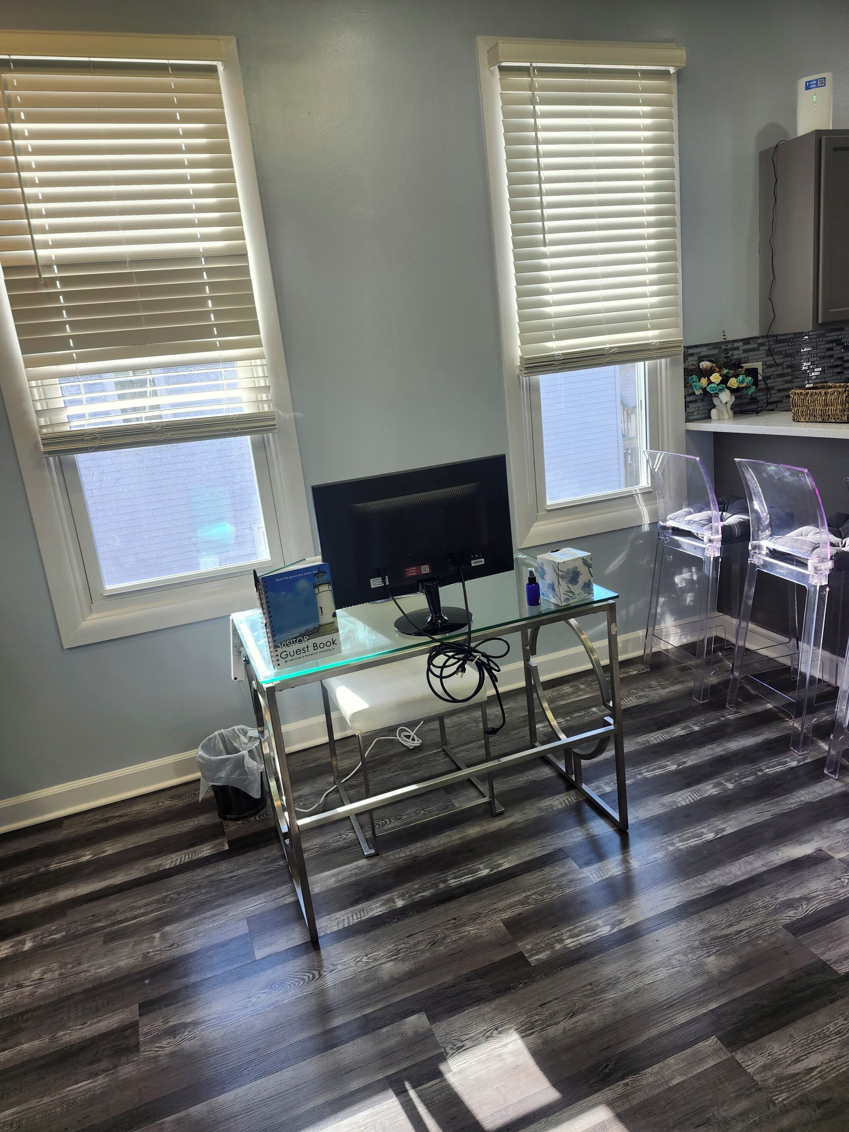 Une pièce comprenant un bureau, un ordinateur et deux fenêtres équipées de stores.