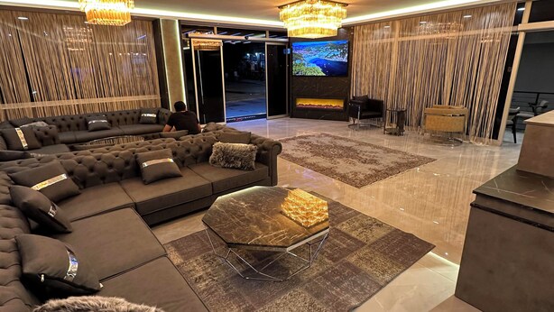 A spacious living area with a large sectional sofa, a glass coffee table, and a modern chandelier. - Comfort Point Two Hotel  (Istanbul)