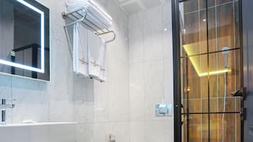 A modern bathroom with a marble floor, a glass shower enclosure, a white toilet, and a vanity with a mirror.