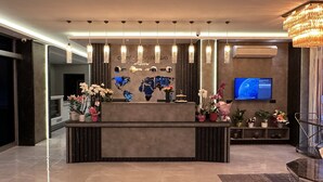 A reception desk with a world map mural, hanging pendant lights, and a television screen. - Comfort Point Two Hotel  (Istanbul)