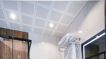 A modern bathroom with a glass shower enclosure, a white toilet, a sink with a mirror, and a towel rack.