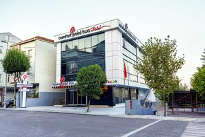 A modern hotel with a glass facade, a prominent logo, and a clear entrance.