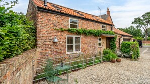 A brick house with a tiled roof, a small front porch, and a gravel driveway. - Haxby Hayloft: A Charming Countryside Retreat Near York (York)