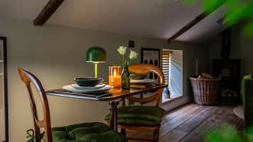 A dining area with a wooden table, chairs, a candle, and a green lamp.