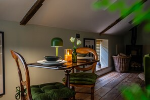 Een eetruimte met een houten tafel, stoelen, een kaars en een groene lamp.