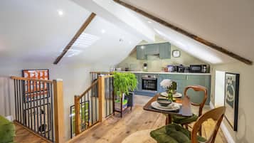 A loft-style living space with a dining area, kitchen, and a staircase leading to an upper level.
