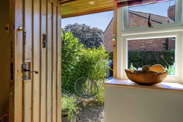 A wooden door with a bell and a window with a wooden bowl on the sill.