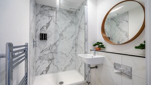 A modern bathroom with a glass-enclosed shower, a white sink, and a marble-tiled wall. - Bootham Row 8: A Cozy City-Centre Retreat in York (York)