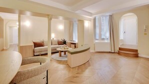 Un salón espacioso con un sofá curvo, una mesa de centro redonda y una zona de estar con un banco curvo.