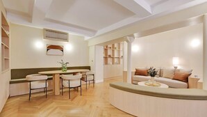 Una sala de estar moderna con un sofá curvo, un comedor con una mesa redonda y sillas, y estanterías empotradas.