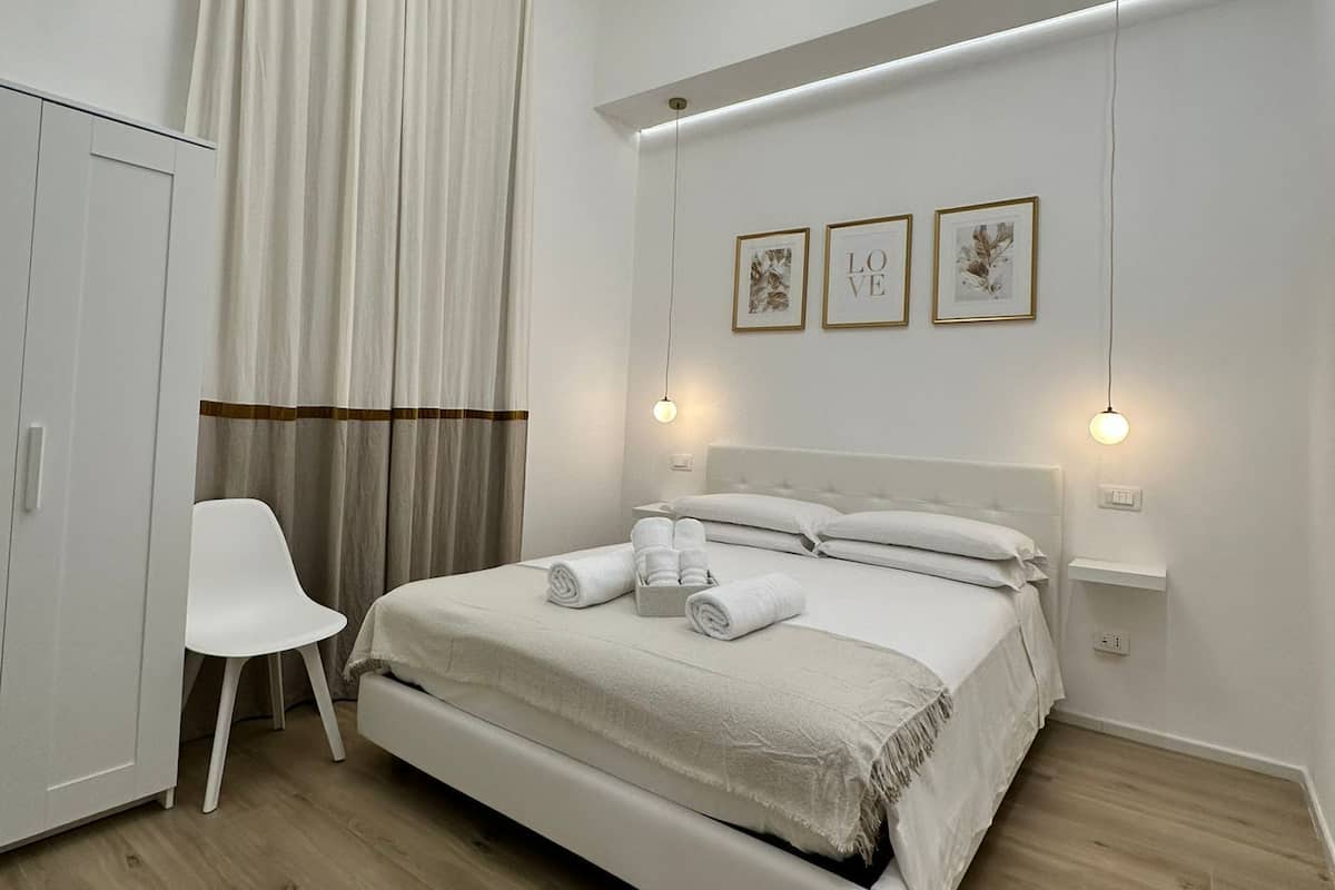 A modern bedroom with a bed, a wardrobe, a chair, and a ceiling light fixture.