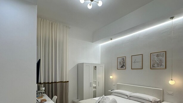 A modern bedroom with a bed, bedside tables, a desk, and a wardrobe. - Center Rooms La Spezia  (La Spezia)