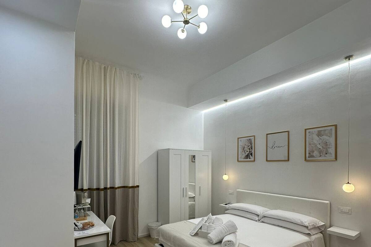 A modern bedroom with a bed, bedside tables, a desk, and a wardrobe.