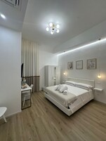 Un dormitorio moderno con cama, mesitas de noche, un escritorio y un armario.