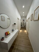 A hallway with a white console table, a mirror, and framed artwork on the walls.