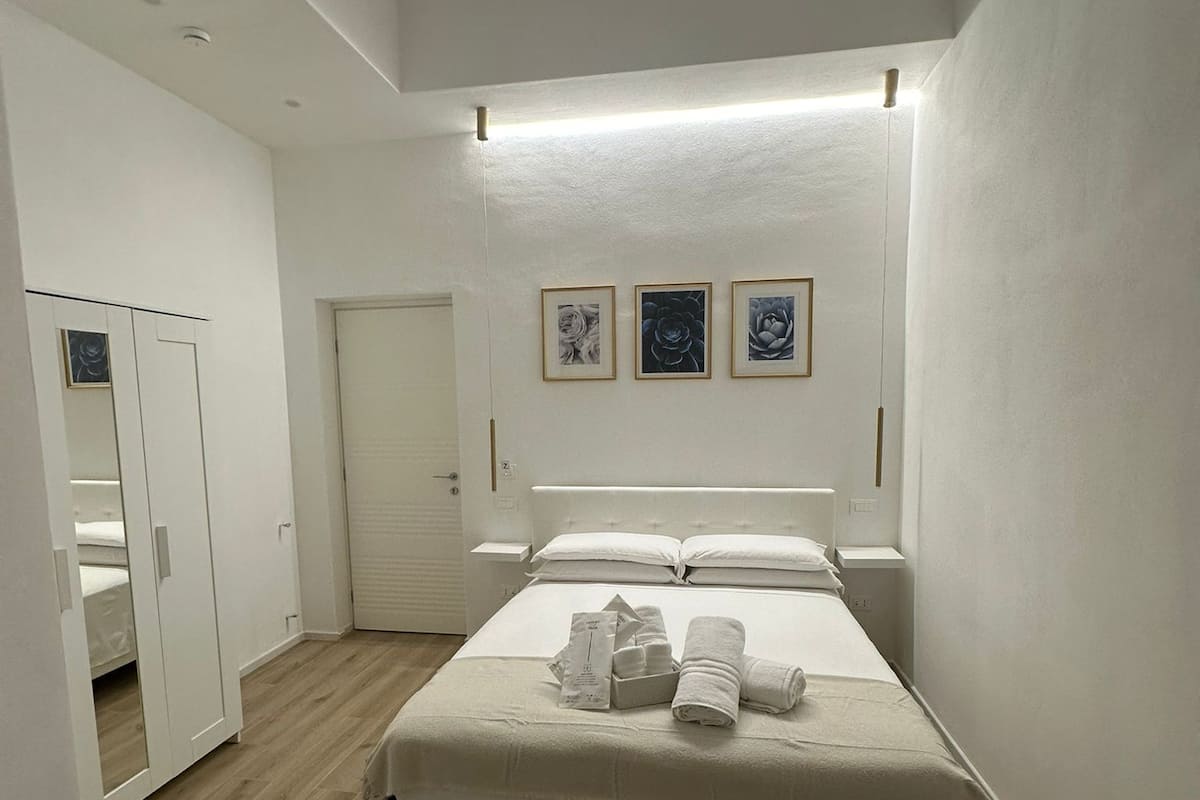 A modern hotel room with a large bed, a wardrobe, and a door.