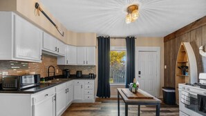Een moderne keuken met witte kasten, een zwart aanrecht en een houten vloer.