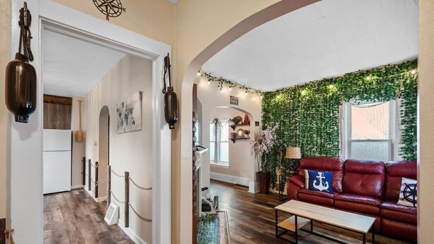 Een gezellige woonkamer met een rode leren bank, een houten salontafel en een wand begroeid met klimop.