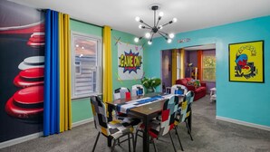 Une pièce chaleureuse et accueillante, agrémentée d’une fresque murale aux couleurs vives, d’un lustre moderne et d’un coin salon confortable.